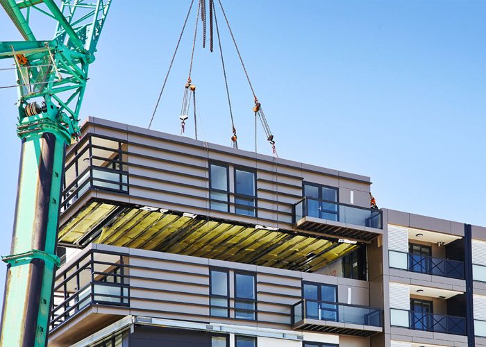 Photo of a modular home section being put into place by a crane